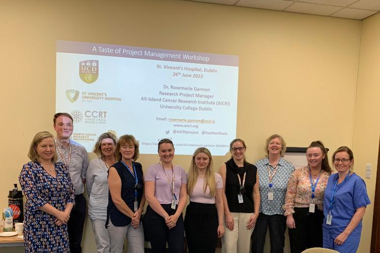 photograph of the St vincent's hospital clinical trials team standing in a conference room in front of a projected slideshow